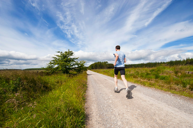 Person running on a country trail under a blue sky