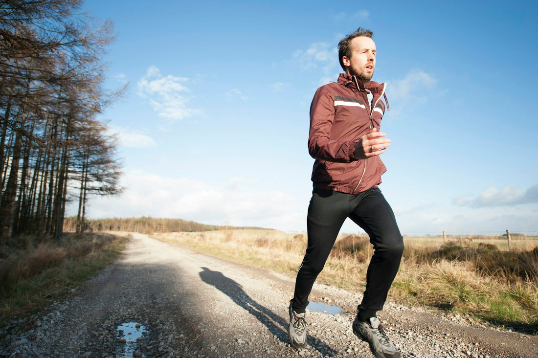 A man running on a gravel trail under a bright blue sky