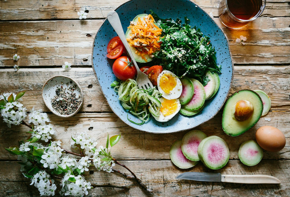 A healthy meal of egg, vegetables, tomatoes and avocado on a blue plate