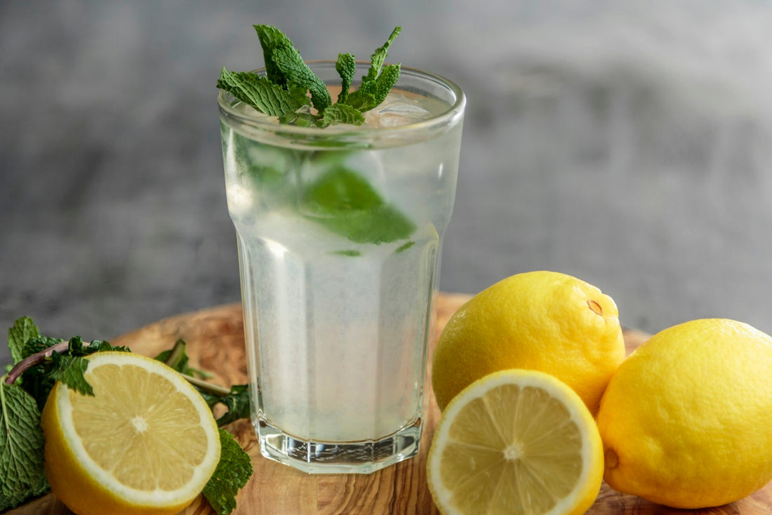 A glass of citrus juice beside fresh sliced limes