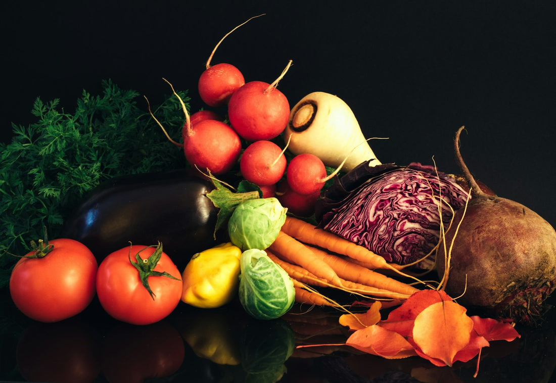 Colourful fresh vegetables including tomatoes, peppers, carrots and cabbage on a dark background