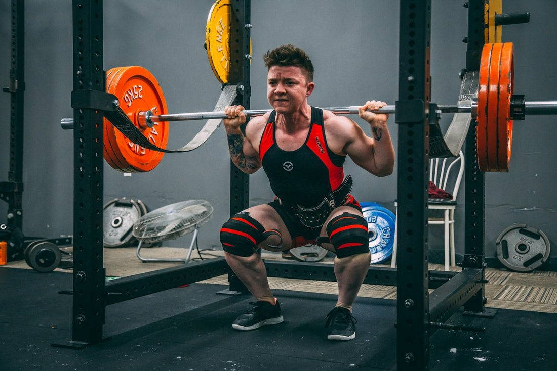 A man performing a barbell back squat in a squat rack in a gym