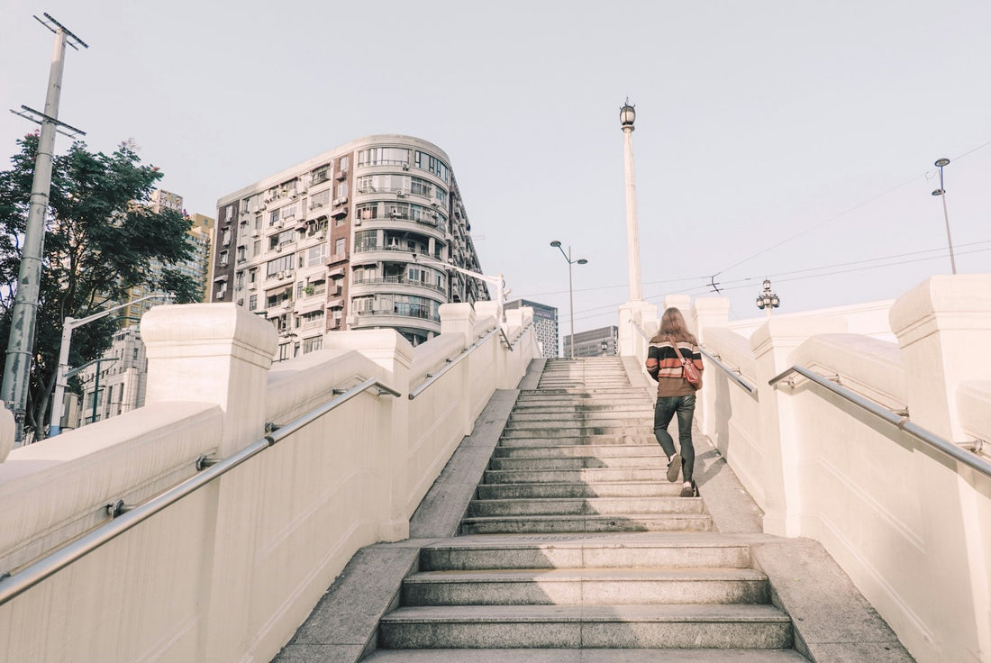 A person climbing a flight of outdoor city stairs on a bright day
