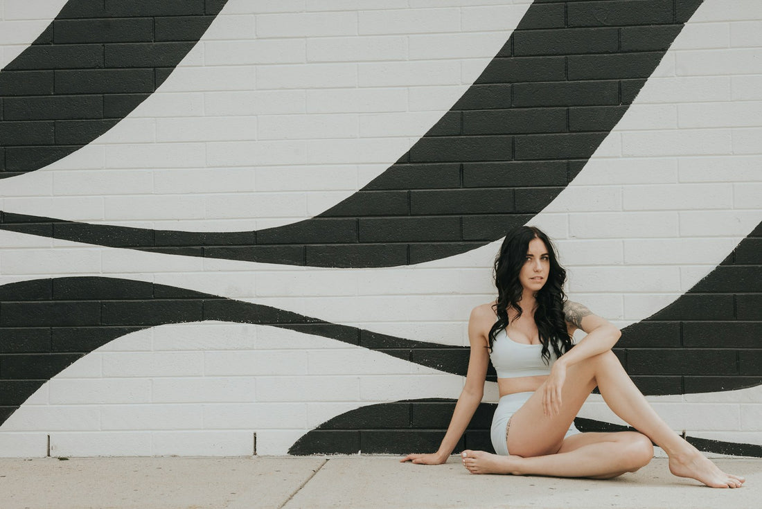 Athletic woman seated against a wall during a workout