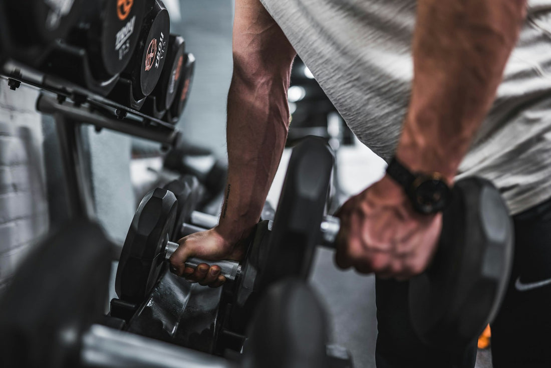 Person lifting a dumbbell from a gym rack