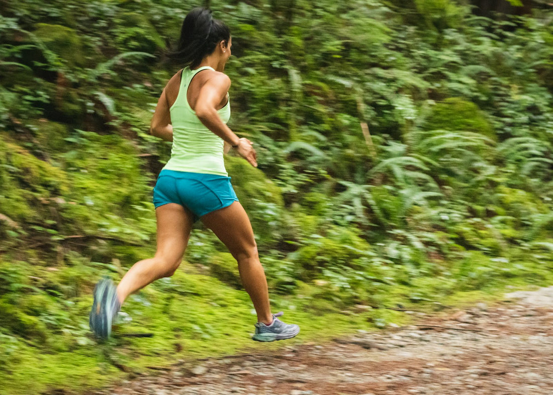 A person running along a forest dirt trail in daylight