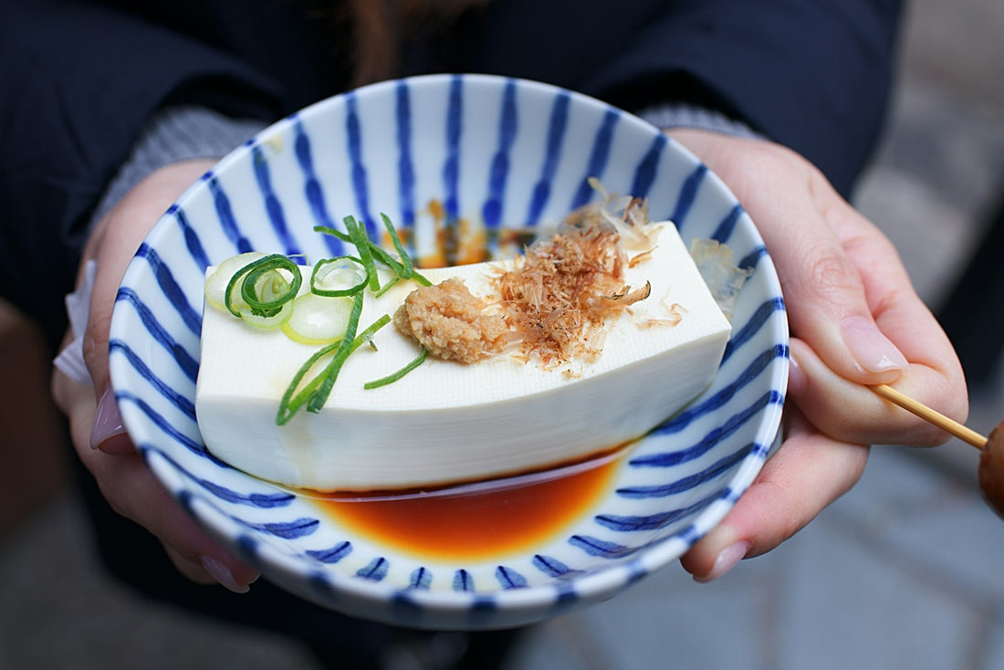 Fresh silken tofu in a blue and white bowl with soy sauce and spring onion