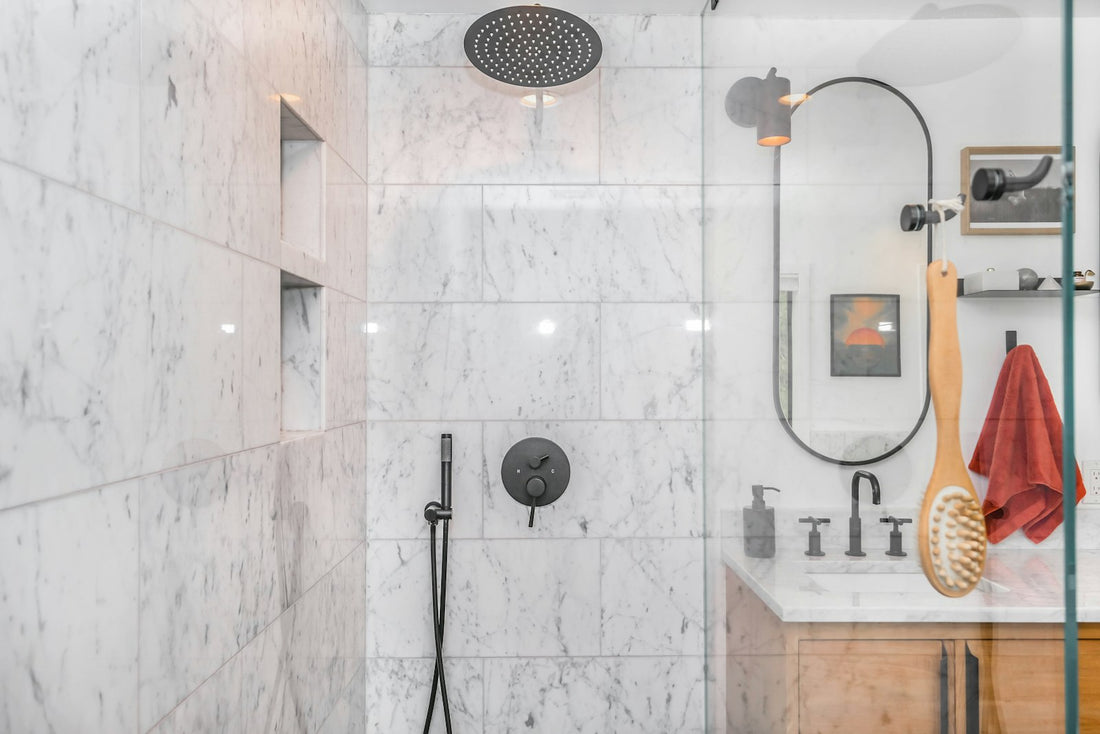 Shower head spraying water against white tiles