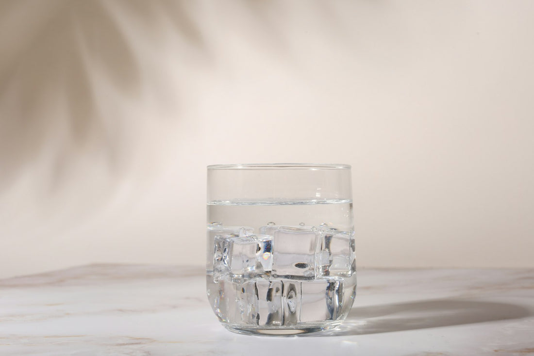 A clear glass of iced water on a marble surface
