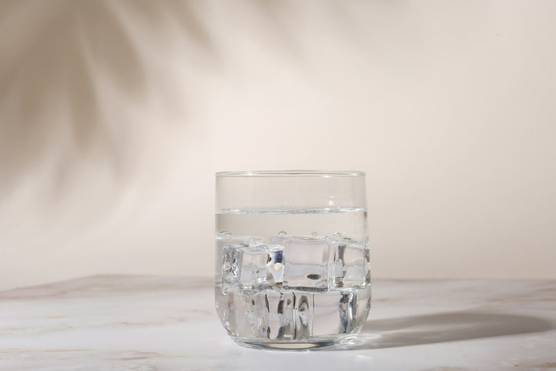 A clear glass of iced water on a marble surface