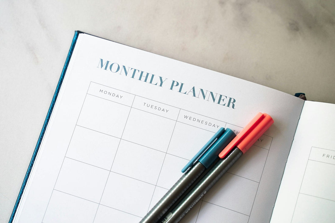 An open daily planner with two pens on top