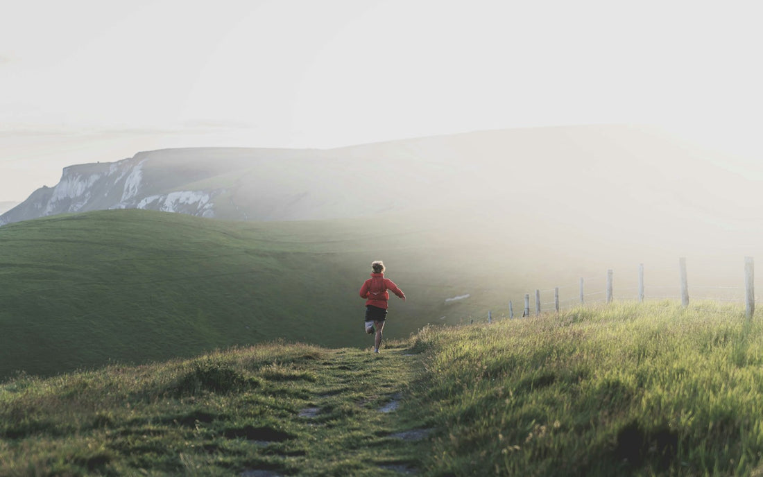 A runner sprinting along an outdoor track at sunset