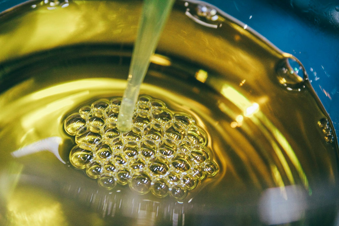 Golden cooking oil being poured into a bowl of oil