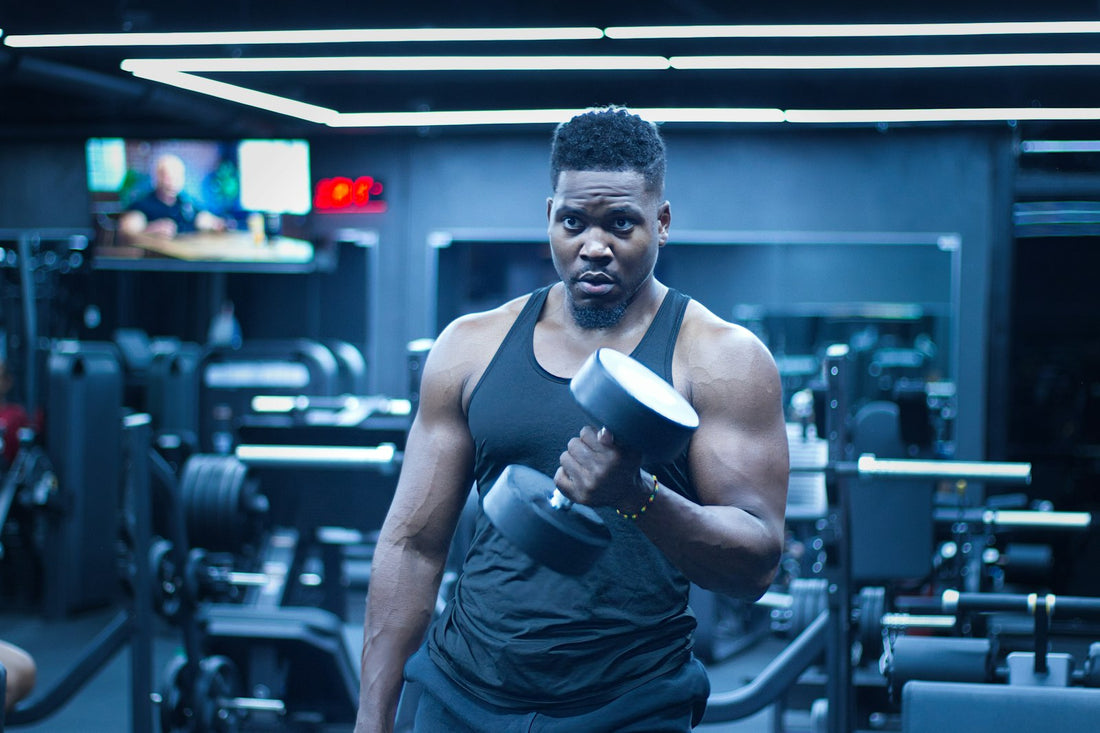 A man performing a dumbbell curl in a well-equipped gym