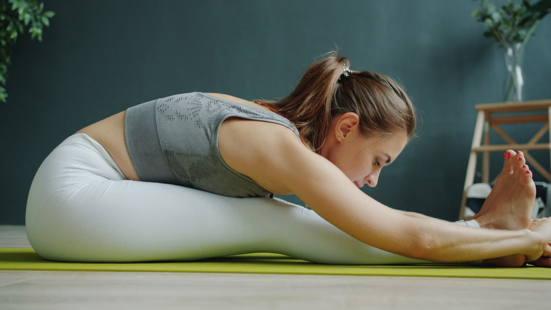 A woman doing a seated forward stretch on an exercise mat