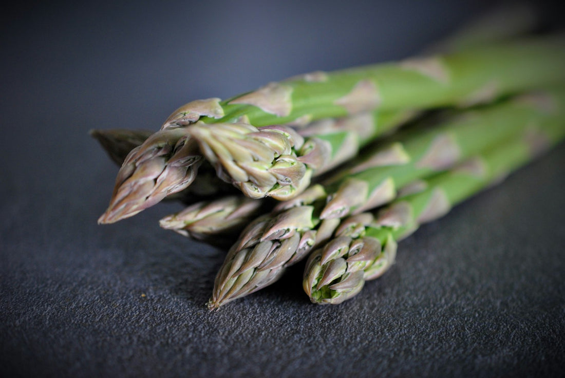 Fresh green asparagus spears on a dark surface