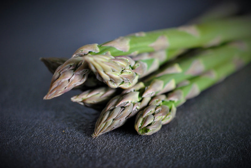 Fresh green asparagus spears on a dark surface