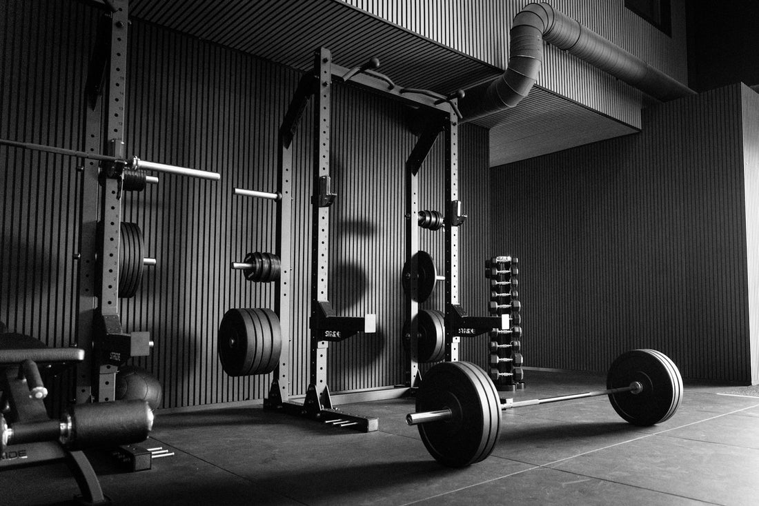 Barbell loaded with weight plates in front of a power rack in a gym
