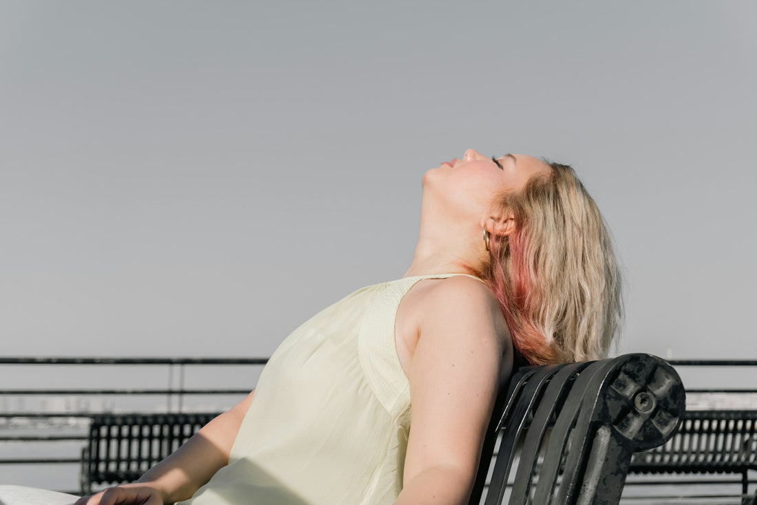 A woman leaning back and relaxing on a bench in soft daylight