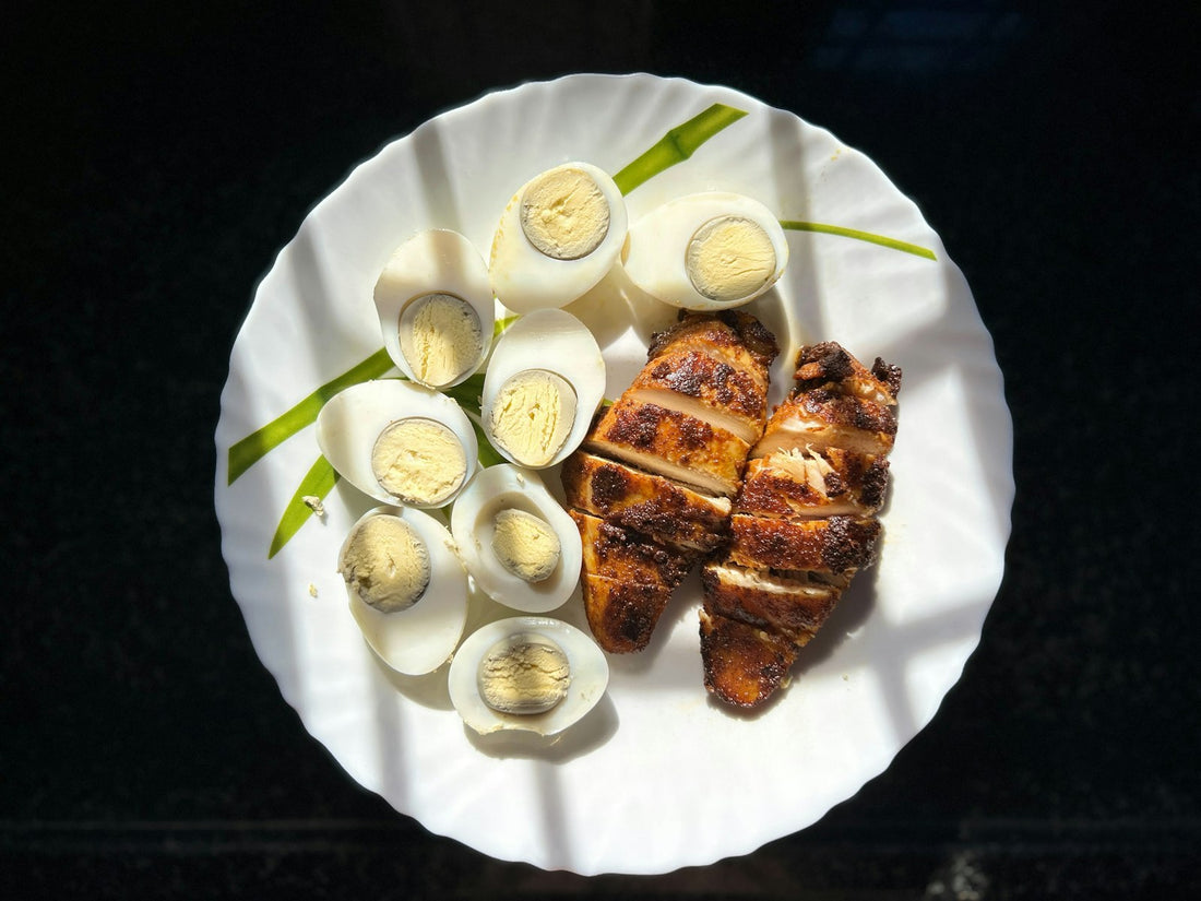 Hard-boiled eggs and sliced grilled chicken breast on a white plate