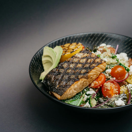 Grilled salmon bowl with avocado and quinoa on a black plate
